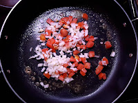 A large frying pan with onion and tomato.