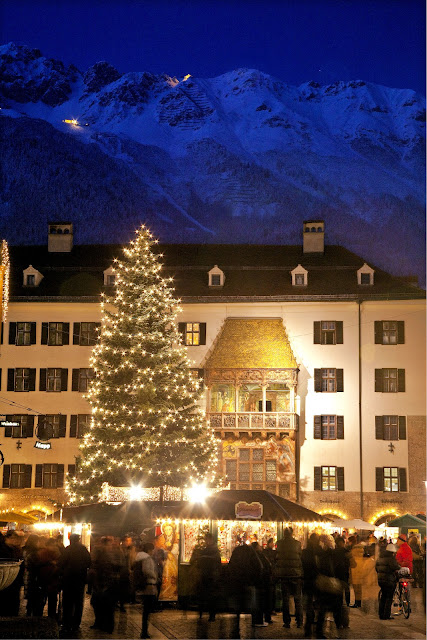 The Alpine mountains provide a stunning backdrop to the Innsbruck Christmas market in Alstadt or Old Town. Here, the Golden Roof shimmers in the warm Christmas light of the market. Photo: © Christof Lackner. Unauthorized use is prohibited.
