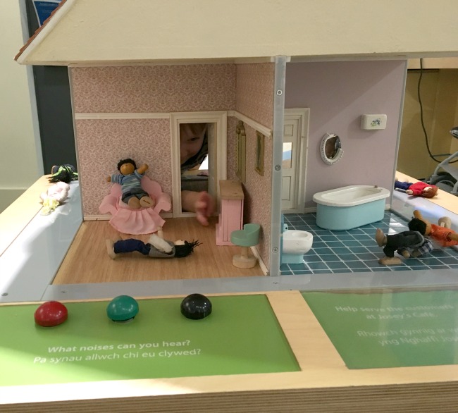 toddler-looking-through-doorway-in-dolls-house
