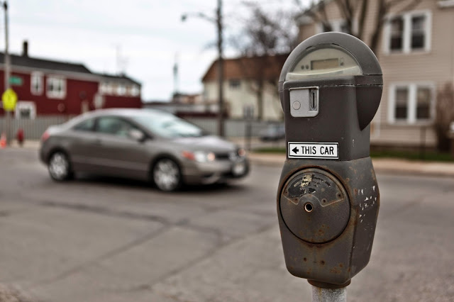 One parking meter pointing at two cars near downtown Milwaukee.