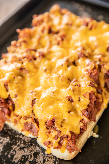 BBQ Ham Sliders - ham cooked in a quick homemade cola bbq sauce and topped with cheese. SO good!!! Great for a quick lunch, dinner, parties and tailgating! Ham, ketchup, cola, onion powder, garlic powder, Hawaiian rolls, cheddar cheese. Can assemble ahead of time and refrigerate until ready to bake. You might want to double the recipe! These don't last long! #sliders #tailgating #partyfood #ham cheese on top of ham rolls