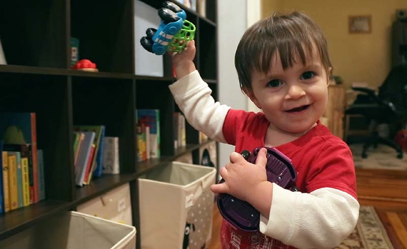 A baby holding his toys
