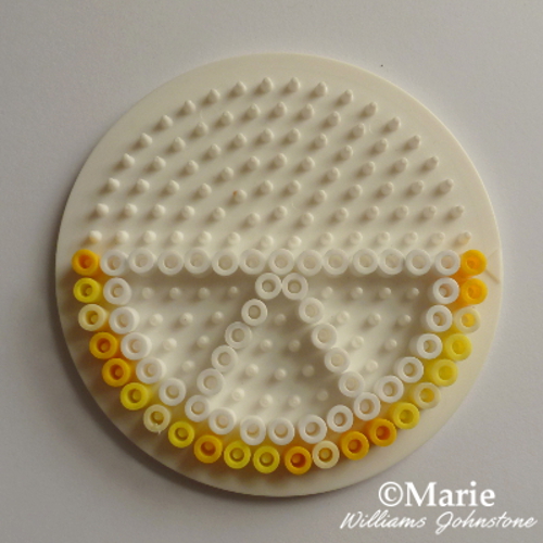 Half lemon slice Perler beads pattern being worked on a circle pegboard