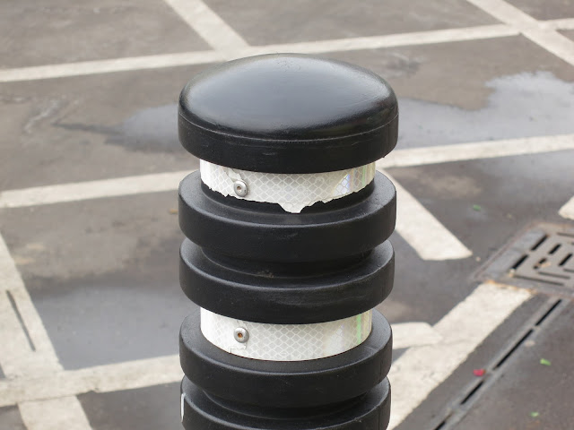 Black and White Bollard and white lines on tarmac