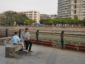 Man and boy sitting next to the Jiangmen River