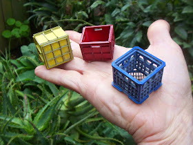 Three modern dolls' house miniature milk crates balanced on a hand.
