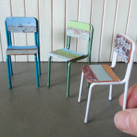 Three one-twelfth scale miniature school chairs with frames painted in seafoam colours and seats and backs made of recycled wood pieces.