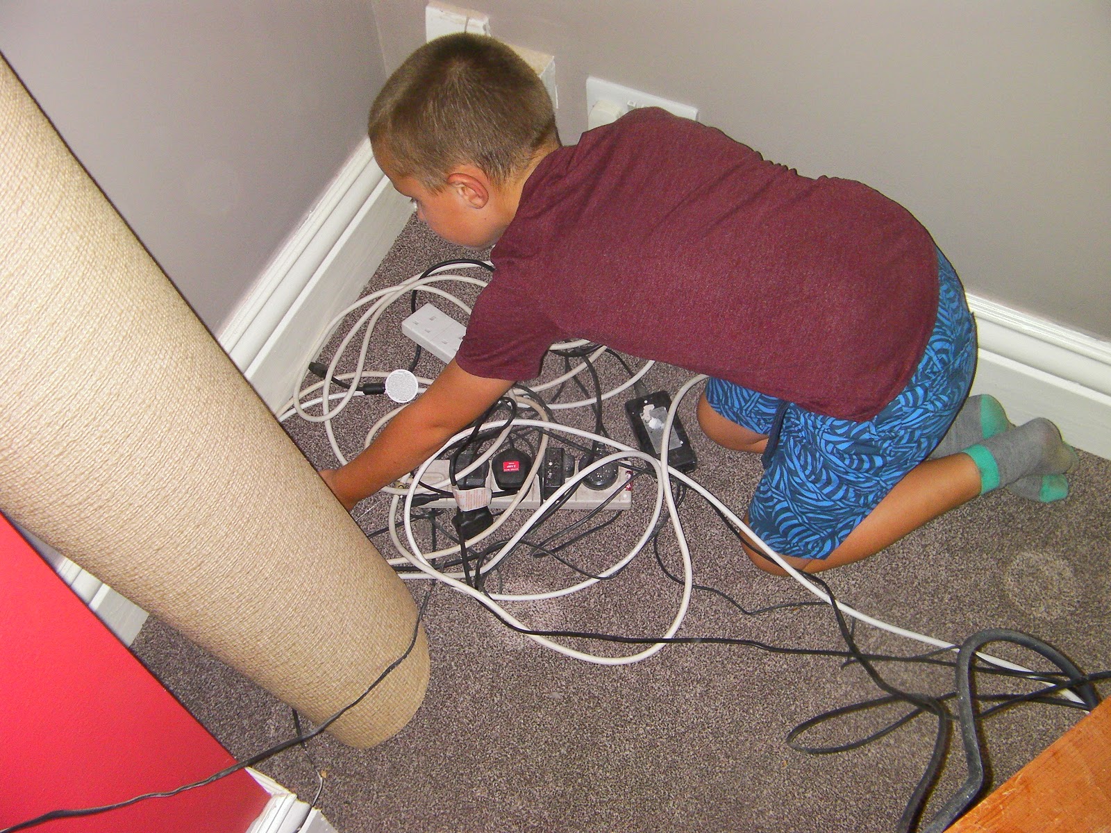 boy hunting mouse holes in skirting board behind tv set