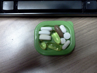 A green dish sitting on a wood desk holding eleven different pills