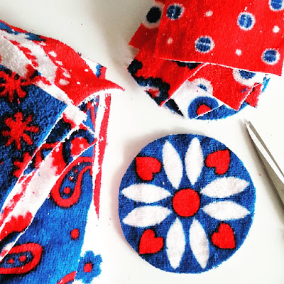 Two piles of cut-up towel pieces in retro designs of white, teal and red next to a pair of scissors.