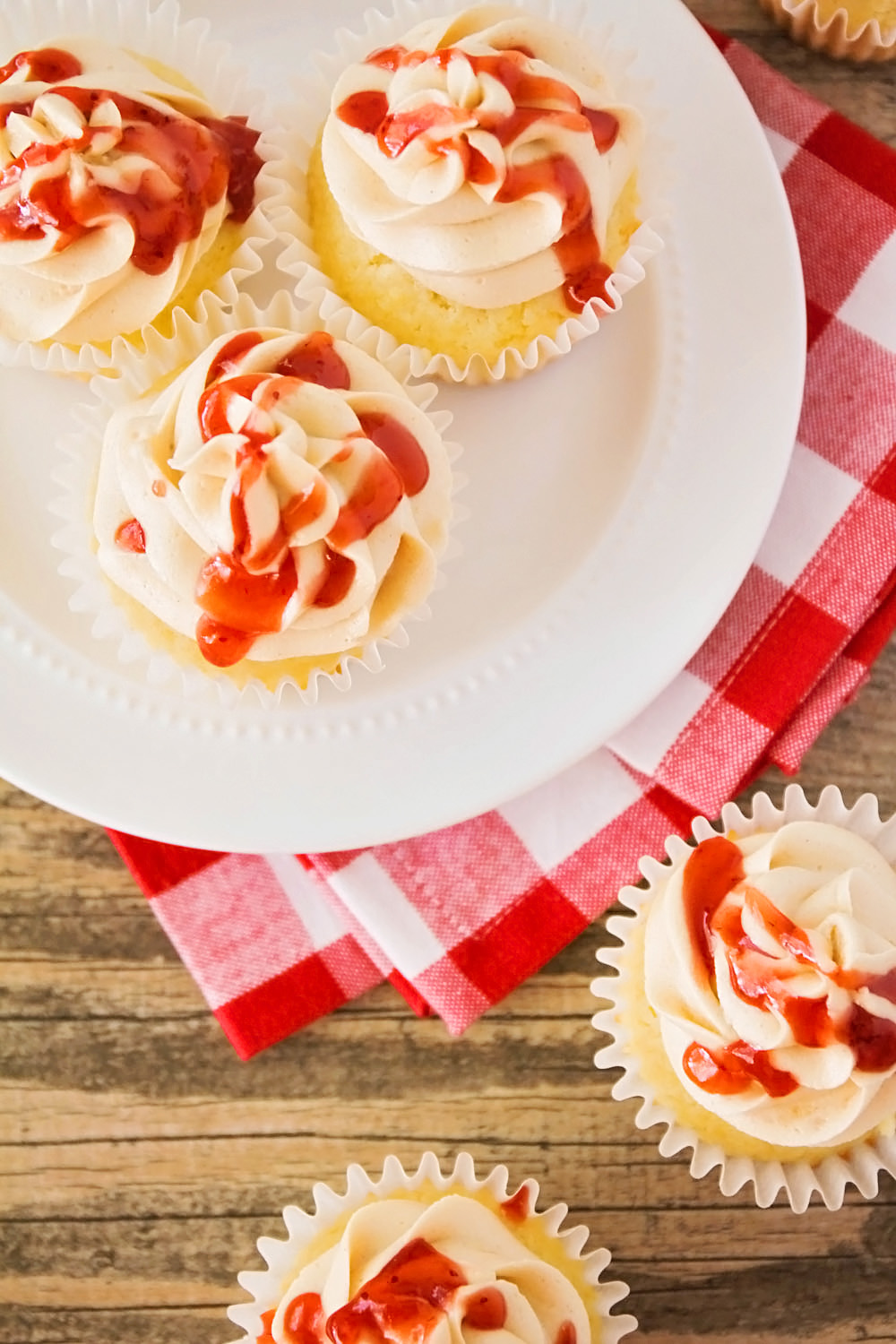 These peanut butter and jelly cupcakes are so fun and delicious! Tender white cake filled with strawberry jam and topped with a delicious peanut butter buttercream. Yum!