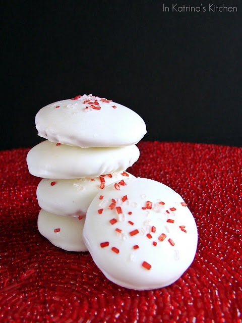 white chocolate covered cookies stacked and sprinkled with red sanding sugar