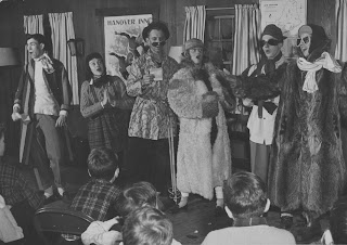 A photograph of a group of people in costume, possibly singing.