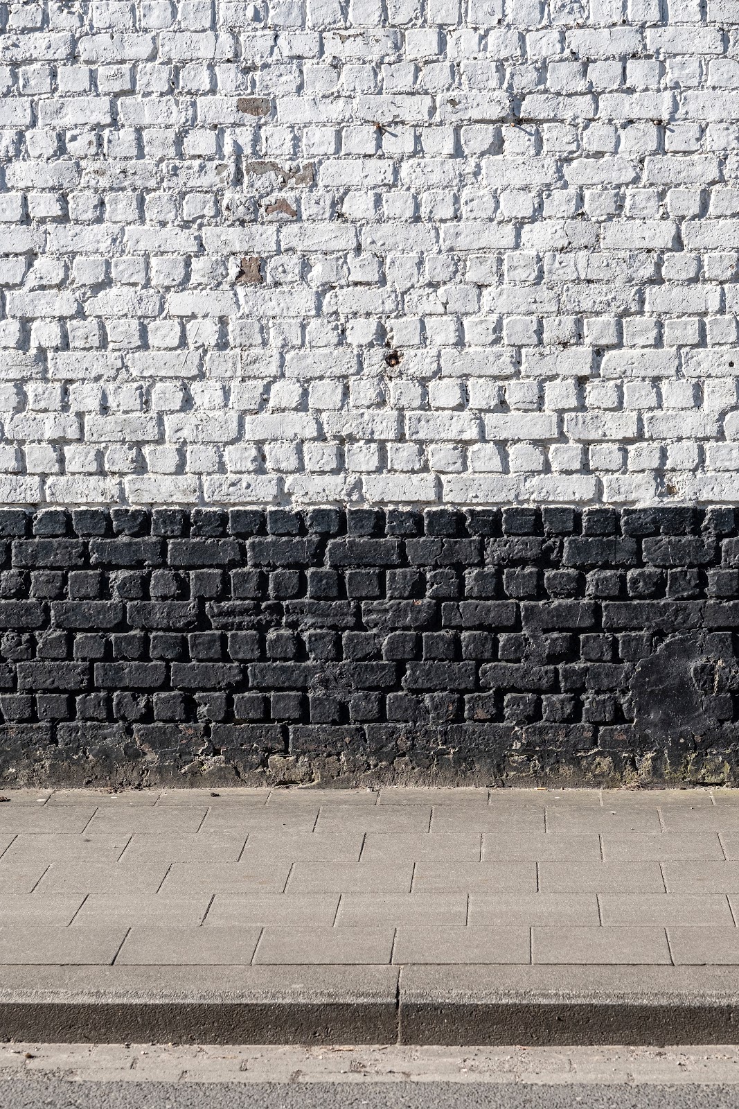 灰色の舗道の上の白と茶色の縦二色の壁