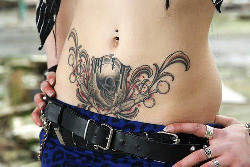 Precioso tatuaje en el abdomen de una chica, el tatuaje de una calavera con jeringuillas