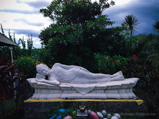 Outdoor Sleeping Buddha Statue In The Sweet Garden At Buddhist Monastery In Bali Indonesia