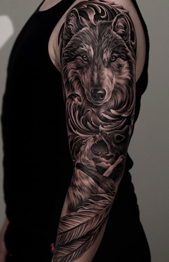 Um majestoso olhando manga da tatuagem. A tatuagem mostra um rosto de um lobo que está aparentemente pronto para um ataque e tem muita determinação n o nos olhos. Abaixo estão mais dois lobos se engajar em uma batalha feroz por superioridade.