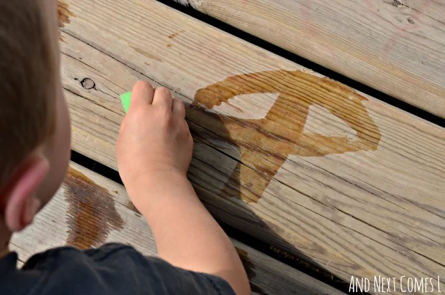 Child writing with water on a wooden deck using alphabet sponges
