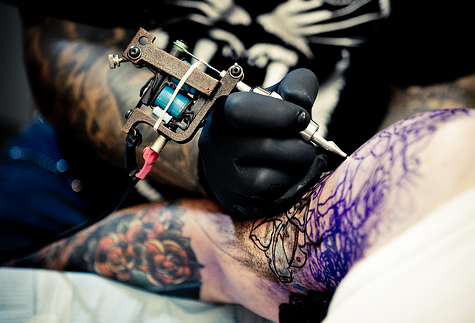 Tatuador realizando delineado en la piel