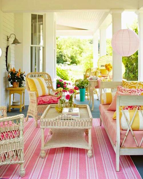 Pink, yellow, and green pops of color look fresh and exciting with white wicker furniture on this spring front porch