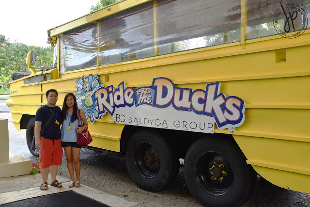 man and woman posing in front of yellow amphibian vehicle