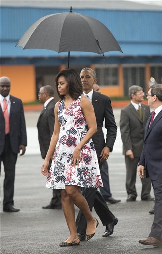 Obama helping  Michelle with the umbrella