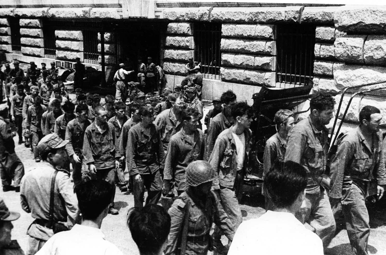 In this undated photo from North Korea's official Korean Central News Agency, American combatants captured during the Korean War march down a street.