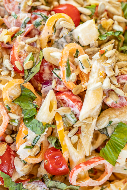 Buttermilk Pasta Salad - the BEST pasta salad ever!! Great for a crowd! Pasta, tomatoes, chives, sweet peppers, basil, cucumbers, onion, sunflower seeds, and feta tossed in a delicious homemade buttermilk dressing made with mayonnaise, lemon juice, hot sauce, garlic, chili flakes and pepper. Add some canned tuna or cooked chicken for a meal! Can make in advance and refrigerate until ready to serve! #easy #pastasalad #recipe #sidedish #pasta close up of pasta salad