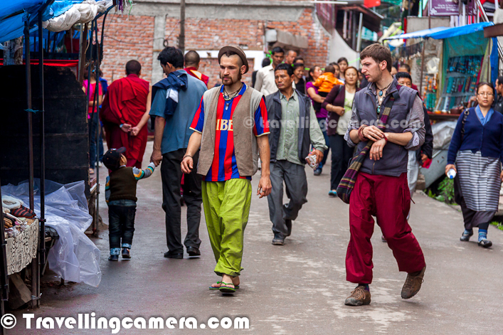Mcleodganj is different kind of hill station in Himachal Pradesh, with different type of culture and environment. This Photo Journey will try to express the main things you notice in this small town near Dharmshala. Let's check out this colorful Photo Journey from Mcleodganj...During your journey towards Mcledoganj, you may not need to reach Mcledoganj for seeing Monks in their interesting dresses. Monks can usually be seen roaming around various places and some of them keep doing some prayers in parallel to other regular activities. Above photograph is shot on road which connects Mcledoganj with Bahgsu Nag Waterfalls. It's sort of mulch-religion shot...Apart from large number of Monks, foreign tourists can be seen in abundance. Most of the street of Mcleodganj can be seen full of tourists from different parts of the world !Colorful cloths, different fashions, innovative hair-styles & lot of different styles can be seen in the streets of Mcledoganj. Overall environment in these streets in quite different.All the streets of this town keep walking most of the time, even when it's drizzling in hills of Mcledoodganj !Many of the tourists come here for different purposes around Yoga, Meditation, Budha etc. During various activities in the town, they got to meet different people and then they enjoy the journey together. You can see many tourists staying in various streets of Mcleodganj for multiple weeks. by looking at them conversing, it seems that they know each other for a long time... A good destination for tourists !Trying various musical forms of India is another big motivation for tourists to come to these hills stations. This girl was standing in front of this shop for around 2 hours and kept playing different flutes. There was no one on shop and she kept waiting that someone would come and she will buy few for her. There are lot of such interesting shops in the streets of Mcleodganj !There are various cloth markets at Mcleodganj, but different styled cloths can be seen in most of them. So it again becomes a good destination for people interested in shopping and especially shopping for trendy cloths.Prayers all around the streets of Mcledoganj !One part of Mcleodganj gives wonderful view of snow capped dhauladhar mountain ranges.Mcledoganj is also a main station in the list birders and peope love to trek Triund which is one of the popular trek around Mcleodganj. Triund is moderate trek, which takes one day only. Sometimes people go uphill with tents and spend one night there.Apart from main temple near Residence of His Holiness Dalai Lama, there is another temple in the middle of Mcledoganj Market. Above photograph is shot at the temple in market.Mcleodganj is also a good place for finding decent range of warm cloths and winter-wear. Above photograph shows a road-side shop with various options of Shawls, sweaters etc.Also there are many art shops, where tourists can step-in and can try thier artistic ideas. Here you see one of the tourist doing some painting and trying to sell these in the street...