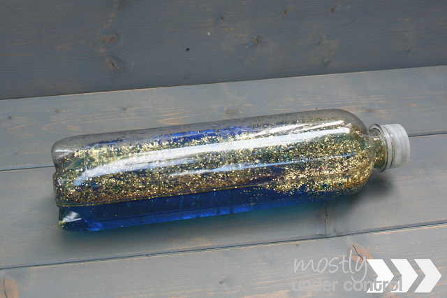 sensory bottle with blue water and gold glitter