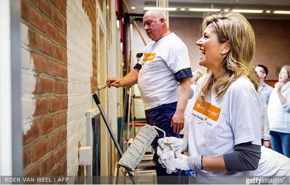 Dutch Queen Maxima laughs as she paints a wall in the sports area of a cultural centre in the village Tricht, on March 21, 2015. Members of the Dutch royal family take part in the national voluntary event NLdoet.