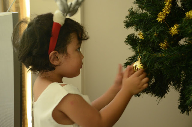 Kecil putting up baubles on the Christmas tree