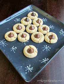 A chewier version of the classic blossom cookie. A soft peanut butter cookie hugs a chocolate candy for a piece of holiday heaven! It just wouldn't be Christmas without them! chew peanut butter blossom cookies topped with chocolate kisses arranged to look like Christmas tree