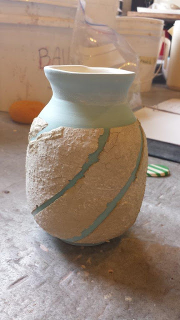 Ceramic vase prepared with sacrificial slip for naked raku firing.