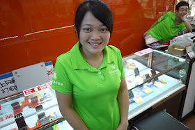 Employee wearing green store shirt with Android and Apple logos.