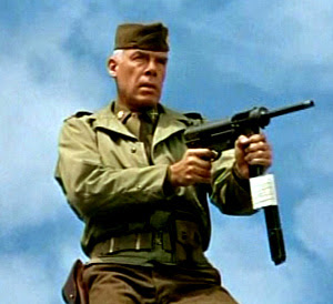 Lee Marvin holding a machine gun in The Dirty Dozen movieloversreviews.filminspector.com