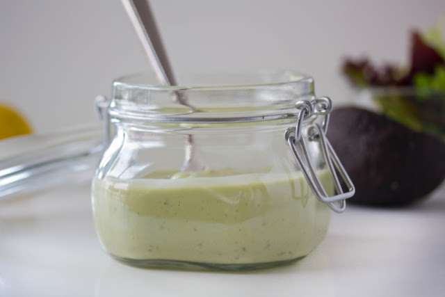 avocado dressing in a glass container with a spoon