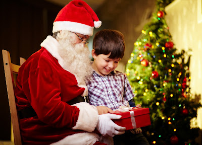 Santa Claus y un niño junto al arbol de Navidad