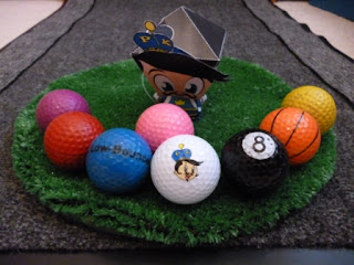 #PKSH2 - The Putter King wobblehead next to 8 different coloured golf balls