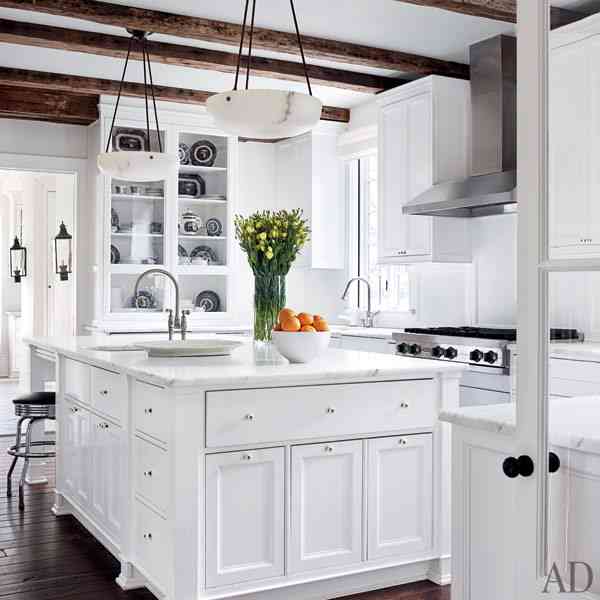 white kitchen with stainless appliances and restained wood flooring