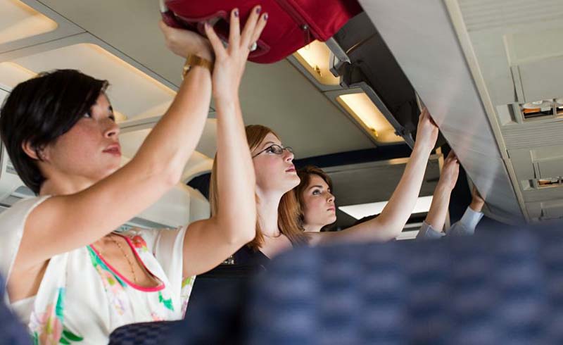 Passengers placing bags in overhead bins
