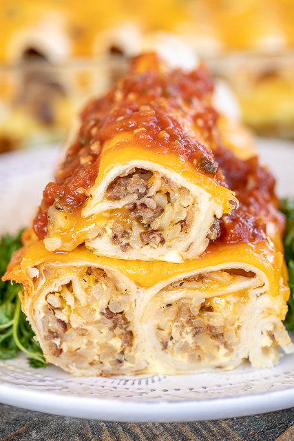 Overnight Breakfast Burrito Casserole Recipe - an easy and delicious make-ahead breakfast casserole! Tortillas stuffed with sausage, hash browns and cheese topped with a mixture of half-and-half, eggs, salt and pepper. Can add onion, bell pepper, spinach, diced tomatoes and green chiles, or mushrooms to the burrito mixture. Great for breakfast, lunch, dinner, baby showers, overnight guests, school mornings, tailgating, and potlucks. This will quickly become a family favorite! #casserole breakfast burritos topped with salsa