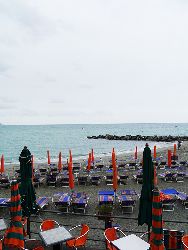 Closed umbrellas on the beach on a cloudy day in Monterosso al Mare, Cinque Terre, Italy