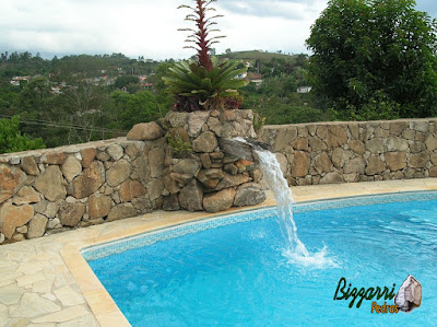 Construção de piscina com muro de pedra, a cascata de pedra com a bica d'água de madeira e o piso com caco de pedra São Tomé.