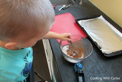 kid stirring together spice mixture for nuts