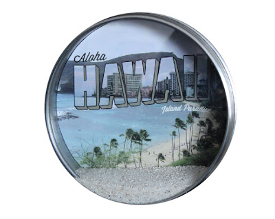 round tin with hawaian image and sand displayed inside