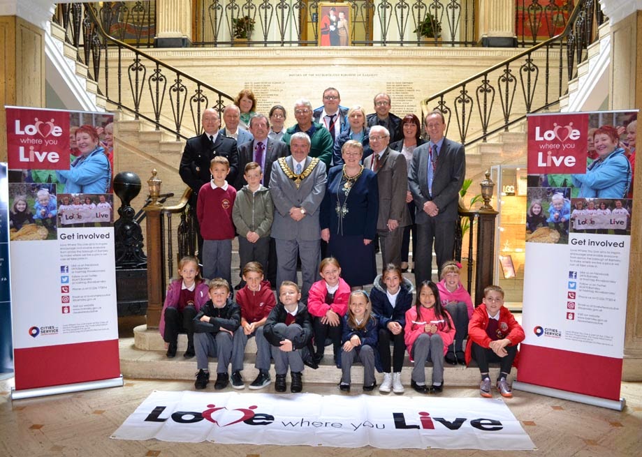 Children, the mayor and mayoress and various helpers standing on the steps inside Barnsley Town Hall.  There is a banner on the floor reading "Love Where You Live".