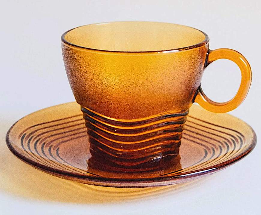 an amber glass cup & saucer an amber glass cup & saucer, a color photograph