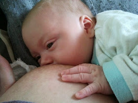 Baby stillt an mütterlicher Brust