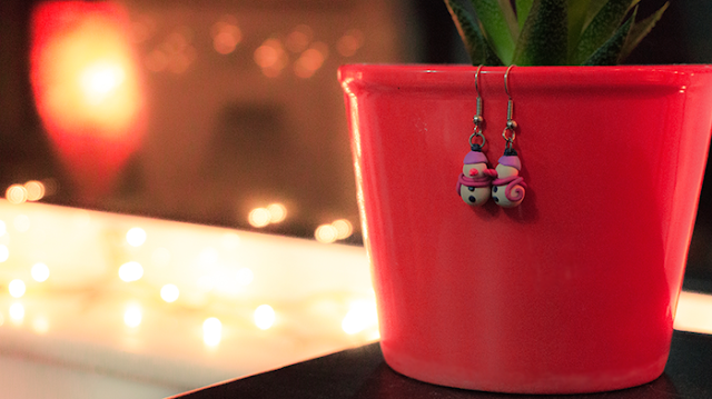 Snowman earrings from polymer clay A pair of snowman earrings hanging from a flower pot and christmas light on the background.